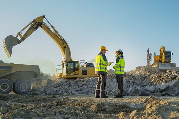 construction workers on a job site with equipment in the background